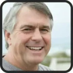 Illustrative portrait photo of a smiling man with grey hair in a grey shirt, a placeholder and not a customer